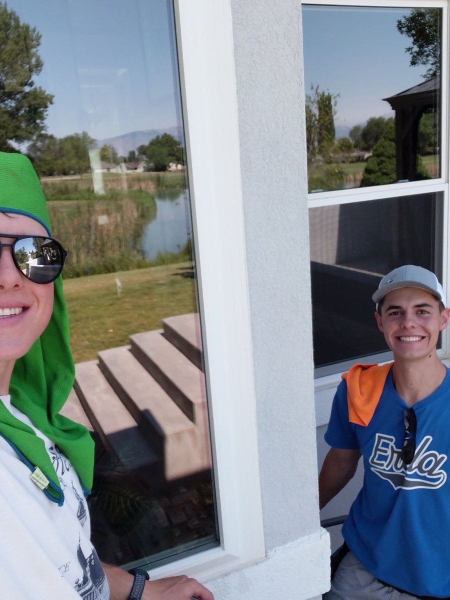Two El Squeegee crew members smiling beside a clean window