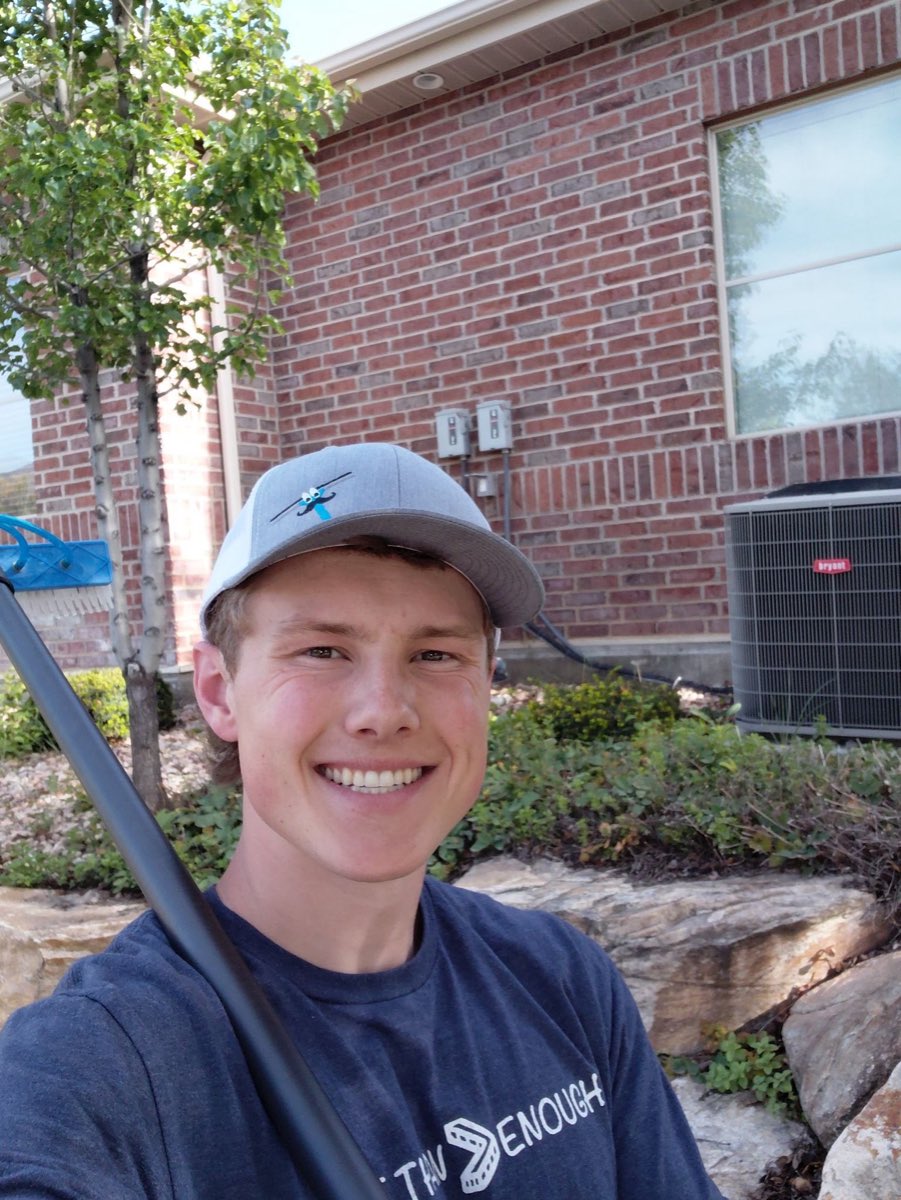 El Squeegee window cleaner smiling on the job outside a brick home