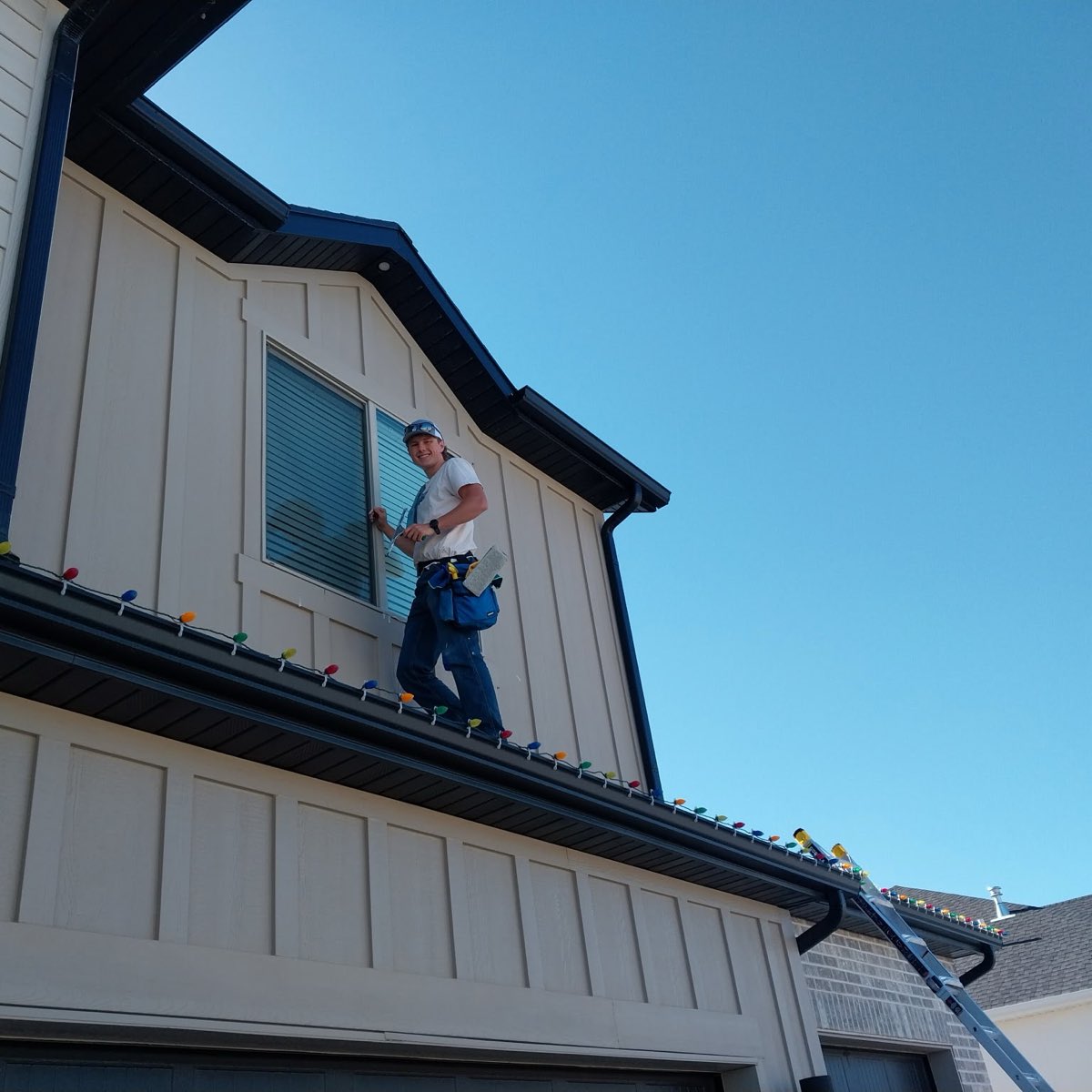 El Squeegee window cleaner working on a second-story window against a clear blue sky