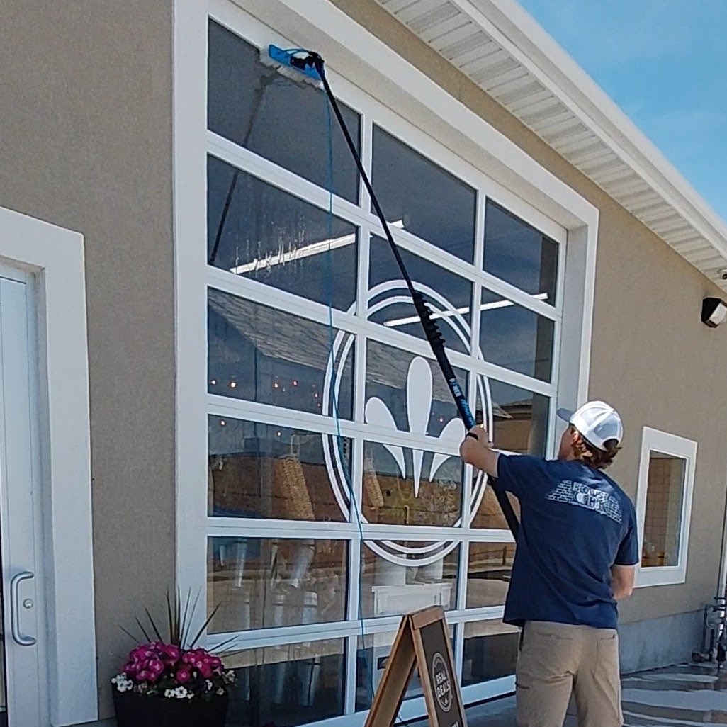Window cleaner using a water-fed pole on a tall commercial glass door